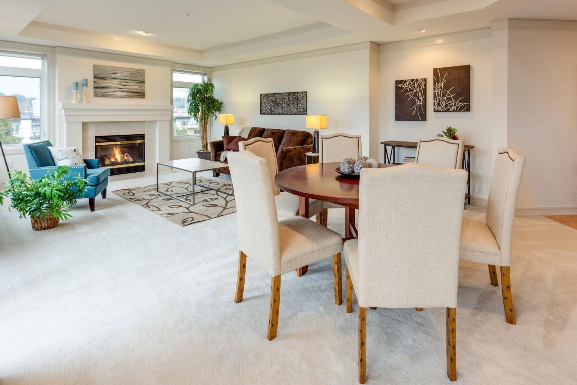 Bright dining room with beige chairs, wooden table, fireplace, and neutral decor