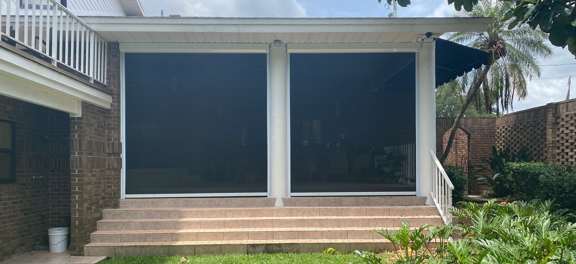 Brick house patio with a screened porch, steps, and sliding doors