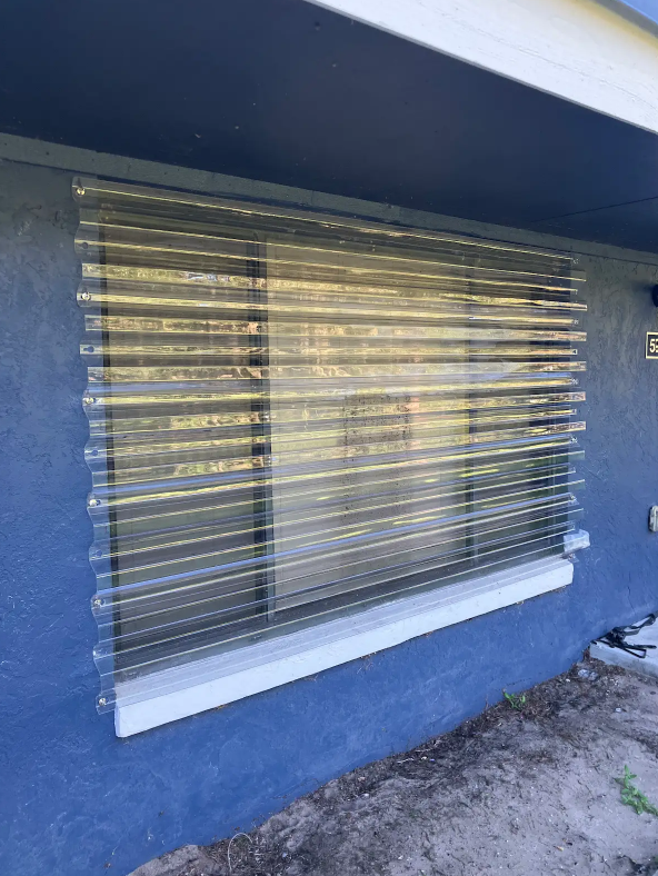 Closed horizontal blinds on a window set in a dark blue exterior wall.