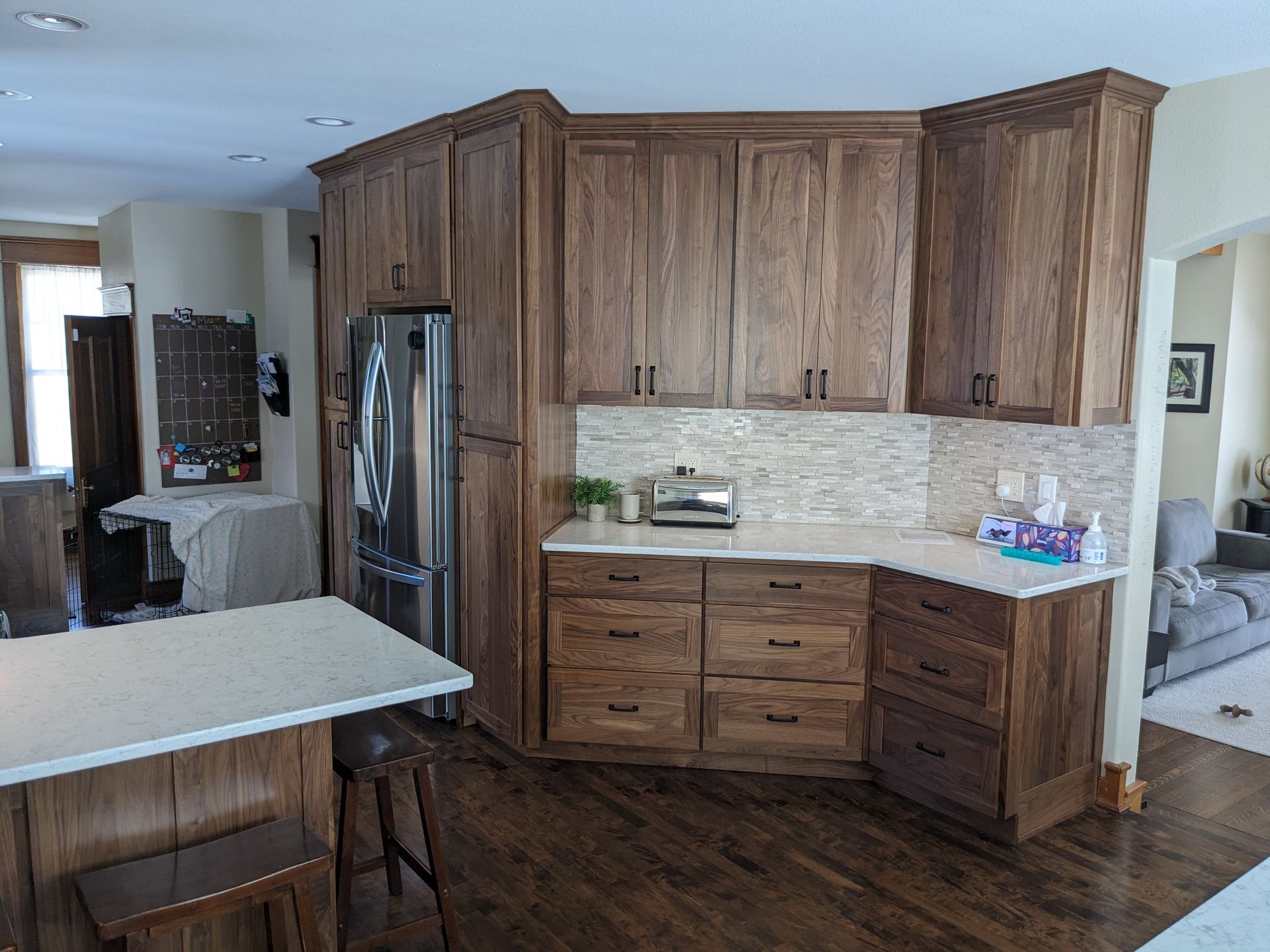 A kitchen featuring dark wood cabinets, a stainless steel refrigerator, white countertops, and a wood island with stools.