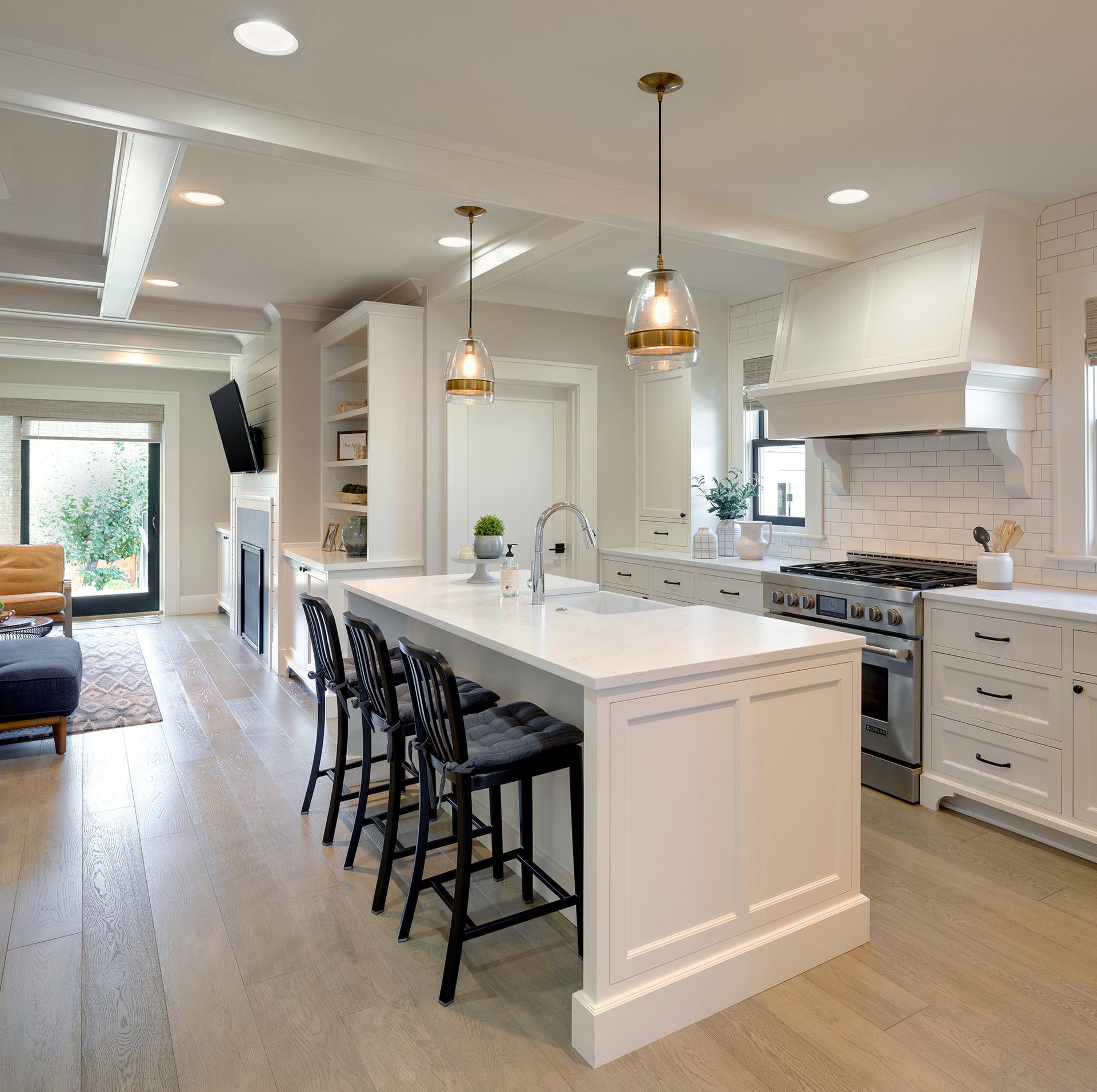 Modern kitchen with white cabinets, gray island, stainless steel appliances, and dark wood floors.