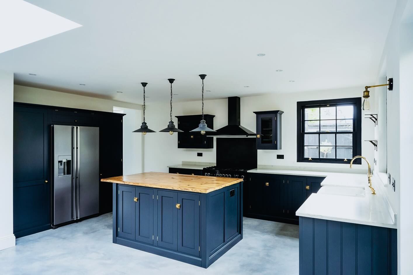 Modern kitchen with navy cabinets, a wooden island, and stainless steel refrigerator.