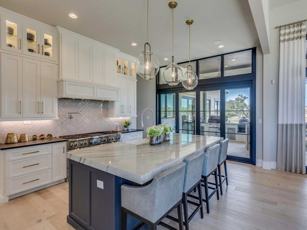 Modern white kitchen with island, blue accents, and glass door to the outdoors.