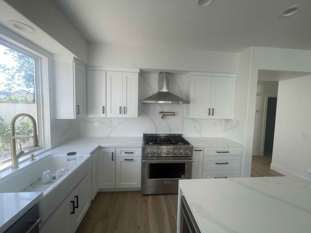 White kitchen with stainless steel appliances, white cabinets, and wood flooring.