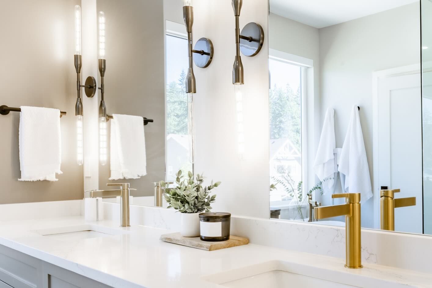 Modern bathroom with gold fixtures, white countertops, and soft lighting.