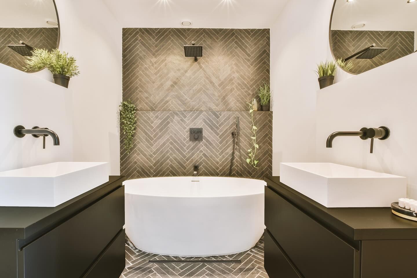 Modern bathroom with a white tub, two sinks, and a patterned tile accent wall.
