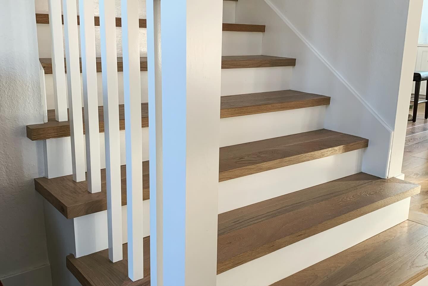 Wooden staircase with white risers and banister, leading upwards.