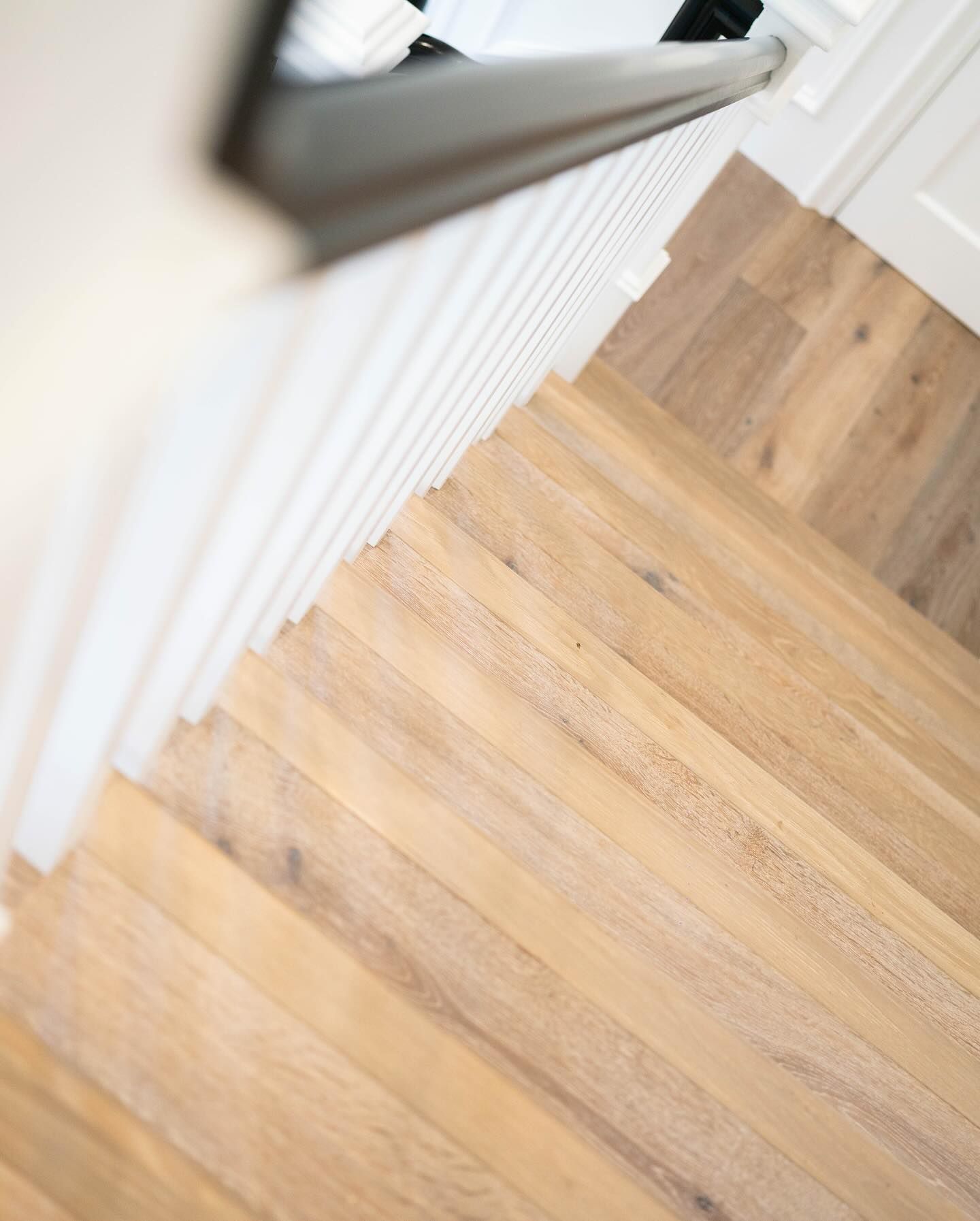 Wooden staircase with white railing and gray handrail.