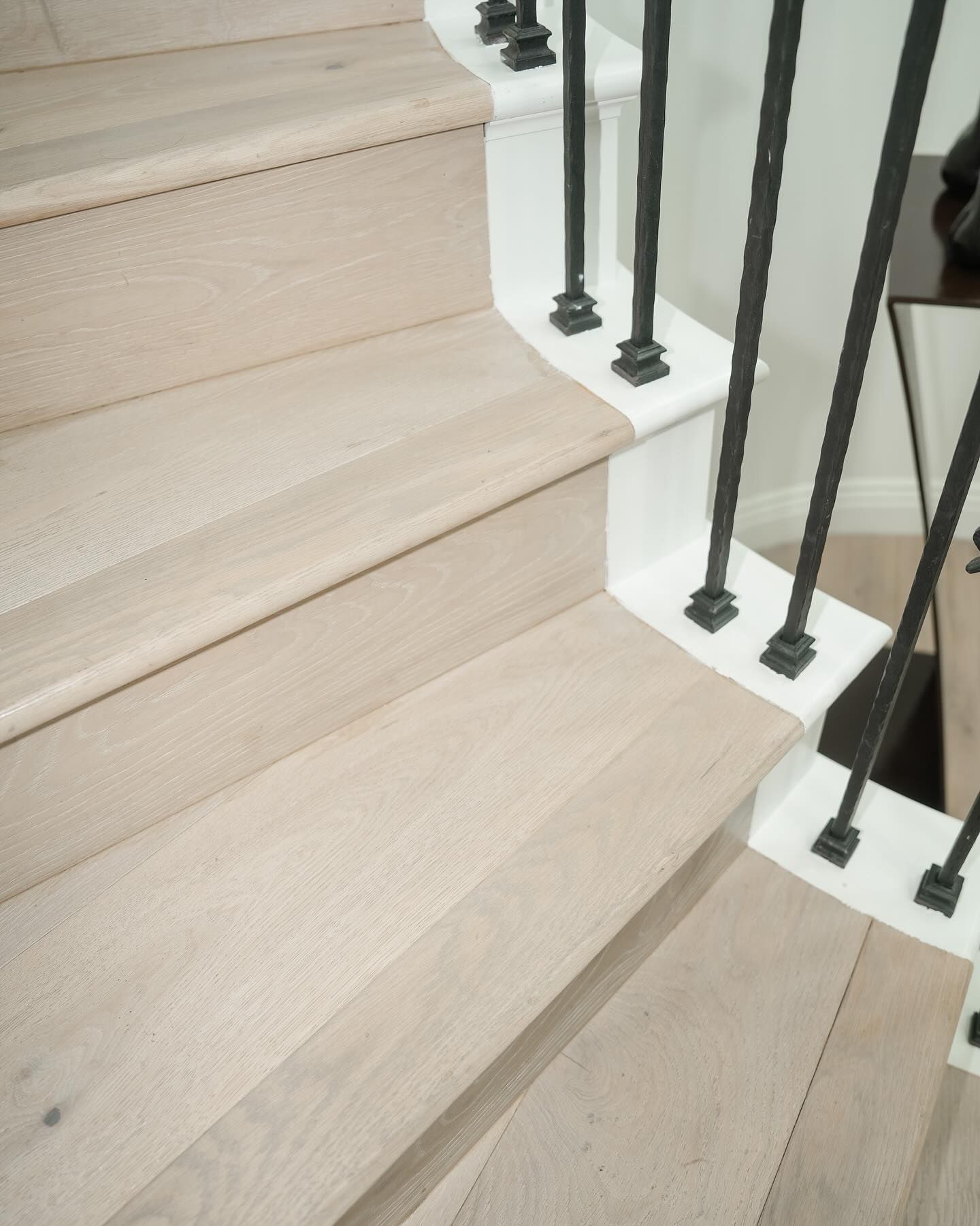 Light wood staircase with white accents and black iron railing.