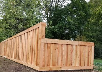 Wooden privacy fence in front of green trees.