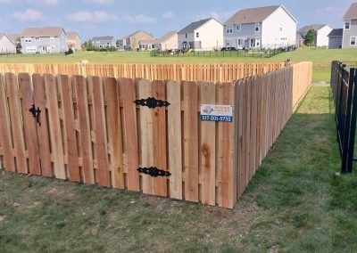 Wooden fence with gate in front yard of suburban homes.