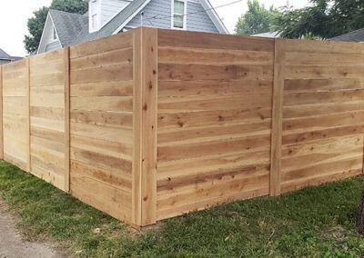 Wooden privacy fence surrounding a grassy yard; a house in the background.