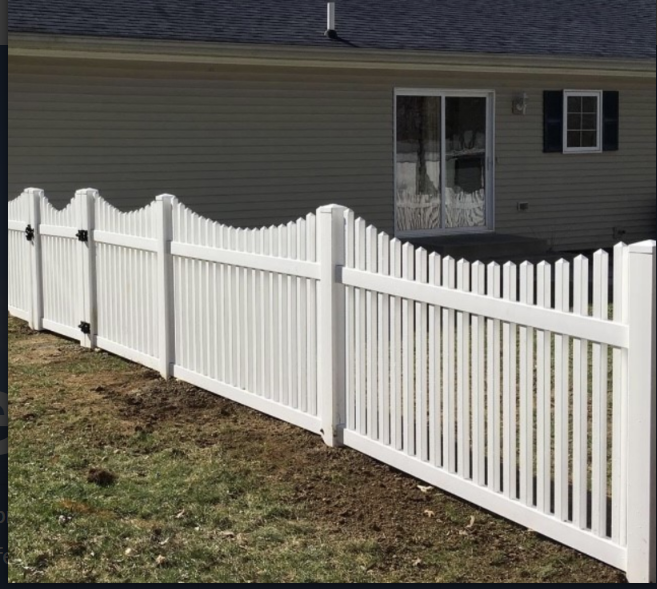 White picket fence in front of a tan house with a sliding glass door and small window.