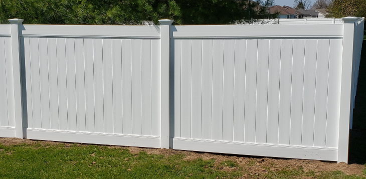White vinyl fence in a grassy yard.