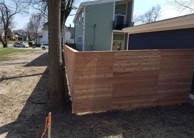 Wooden fence surrounds a building and tree.