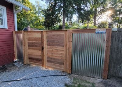 Wooden gate with metal siding sections in an outdoor setting.