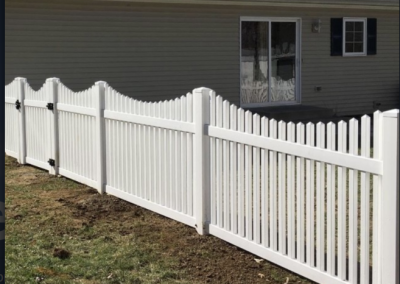 White vinyl fence in front of a tan house with a sliding glass door and a small window.