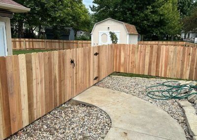 Wooden fence surrounding a yard with a pathway. A shed is in the background.