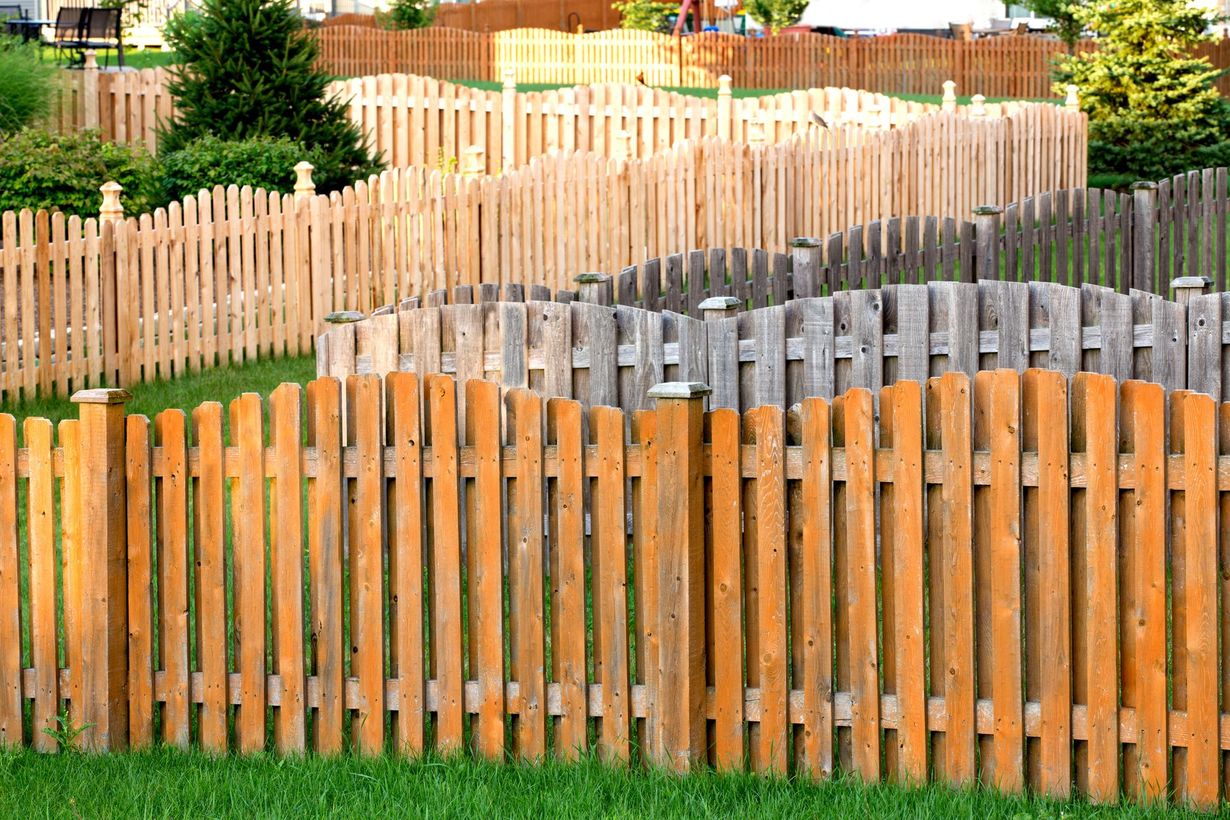 Wooden picket fences of varying colors, undulating across a grassy hill.
