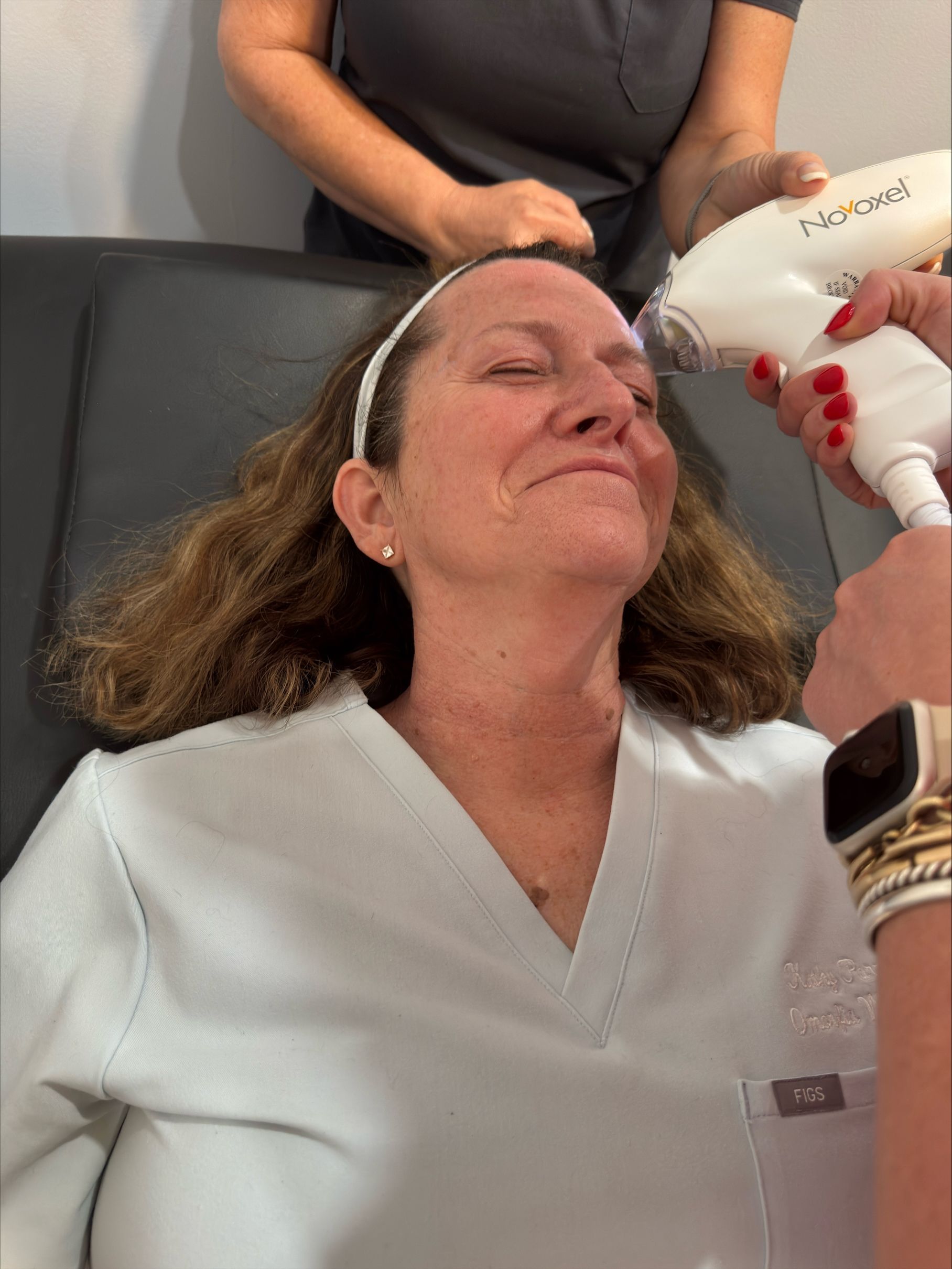 Woman receiving a facial treatment with a handheld device in a salon setting