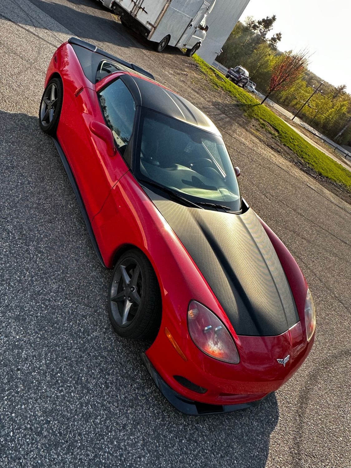 Red sports car with black roof and hood on asphalt.