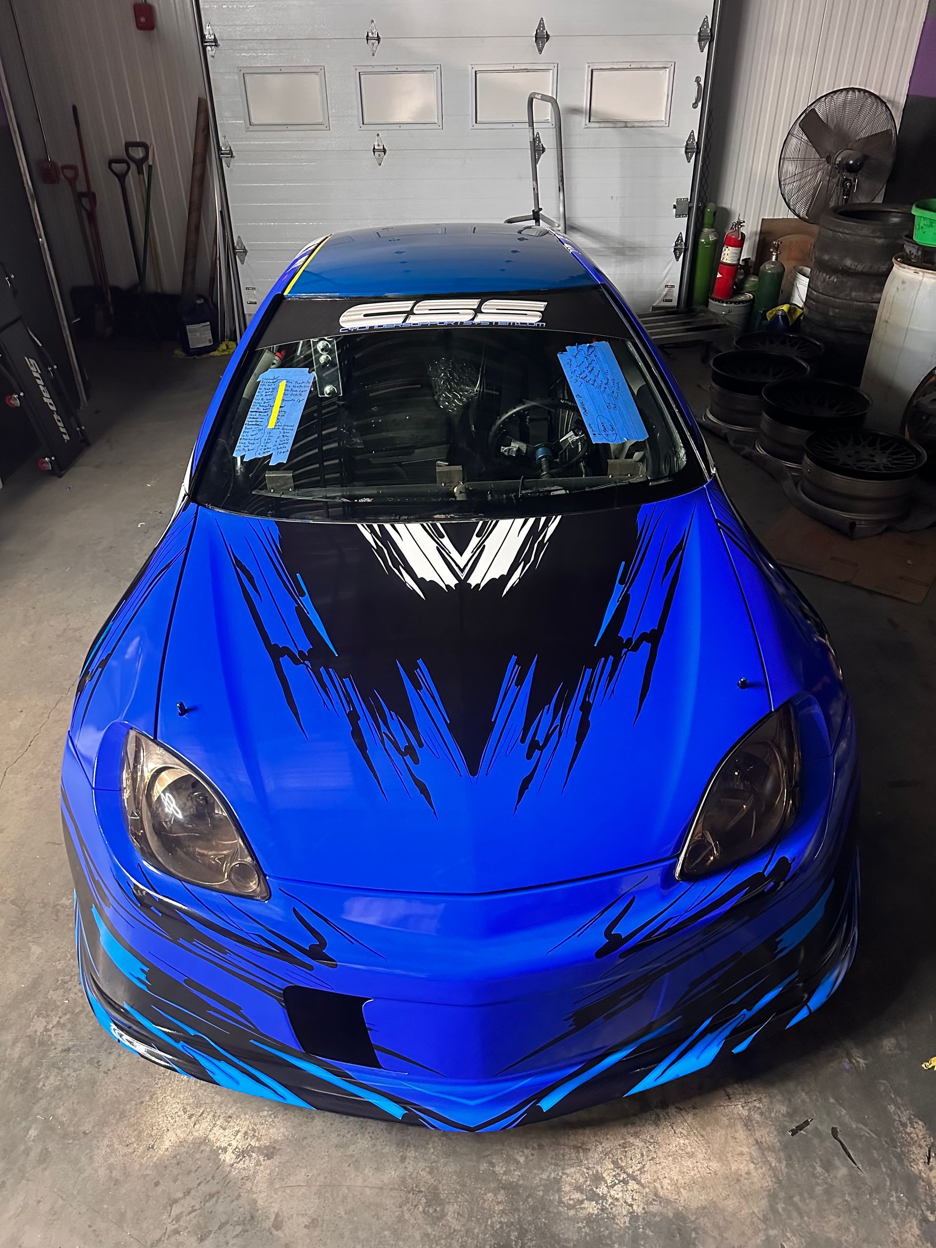 Blue sports car with black accents, parked in a garage.