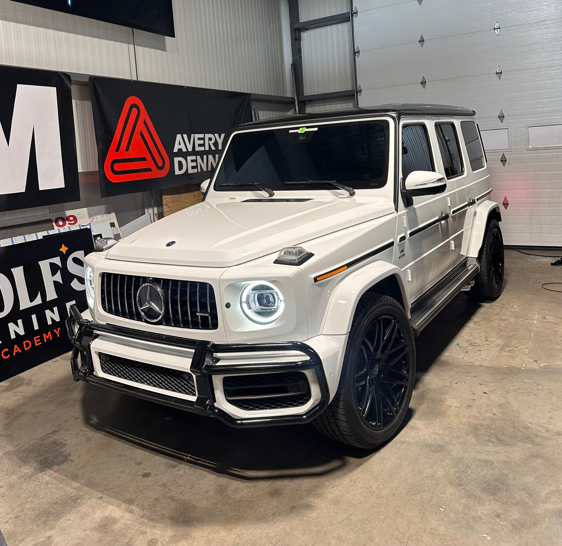 White Mercedes-Benz G-Wagon with black accents, parked in a garage.