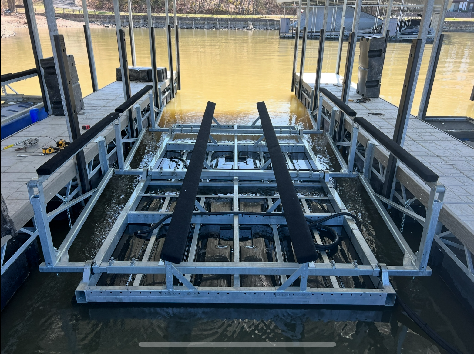 Speedboat docked at pier, facing camera, with other boats in background under overcast sky.
