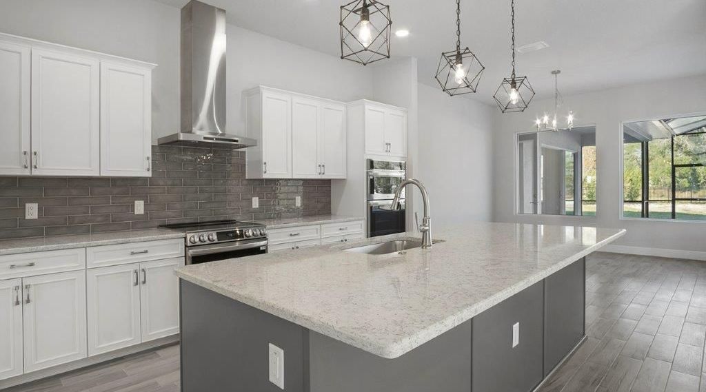 An empty kitchen with white cabinets and a large island.