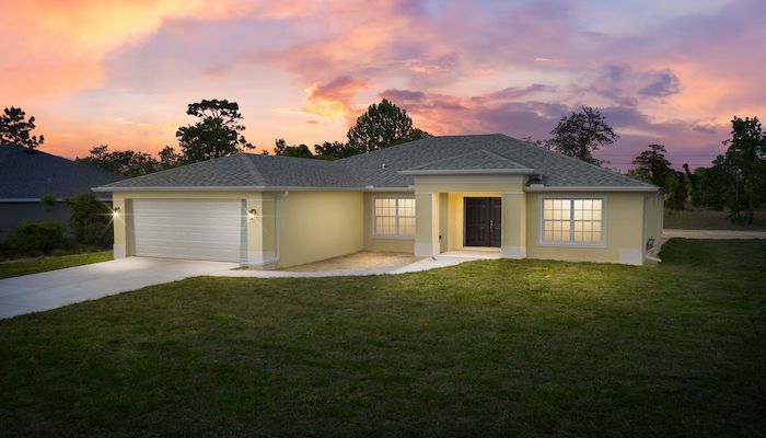 A house is lit up at night with a sunset in the background.