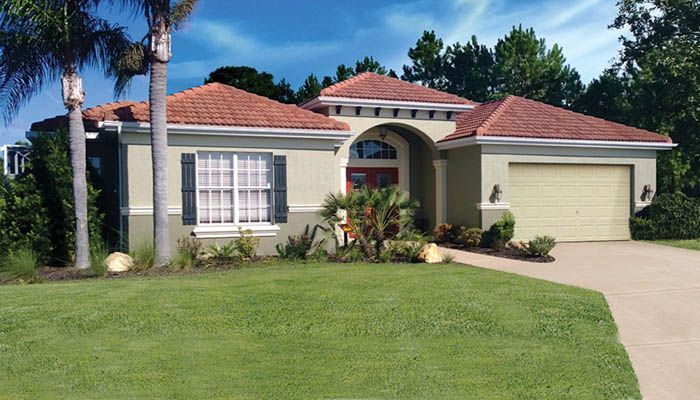 A house with a red tile roof is surrounded by palm trees