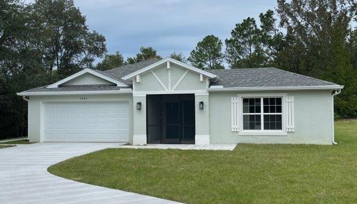 A white house with a gray roof and a driveway in front of it.