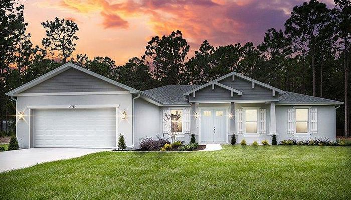 A white house with a garage and a sunset in the background.