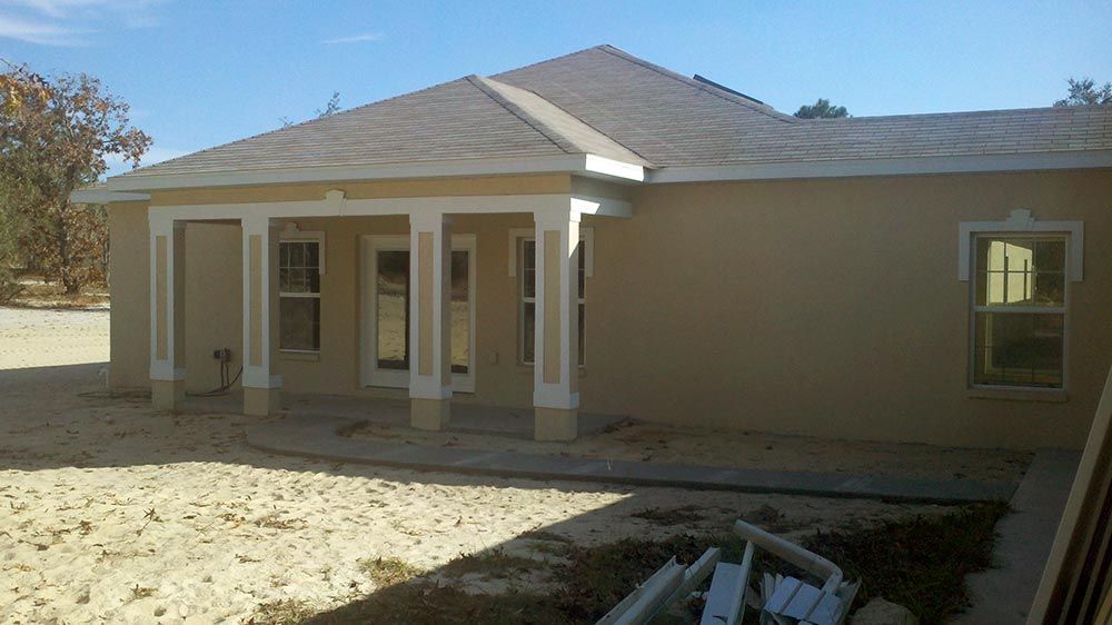 The back of a house with a porch and a lot of windows.