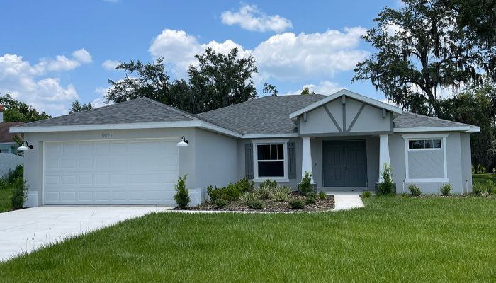 A white house with a gray roof and a white garage door