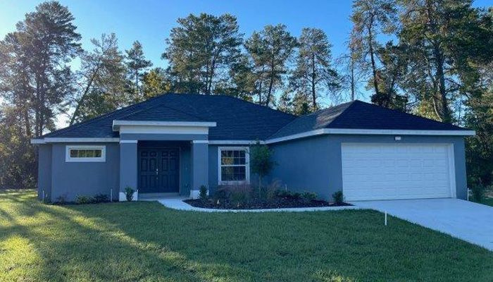 A blue house with a white garage door and trees in the background