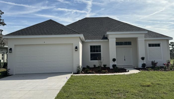 A white house with a gray roof and a white garage door