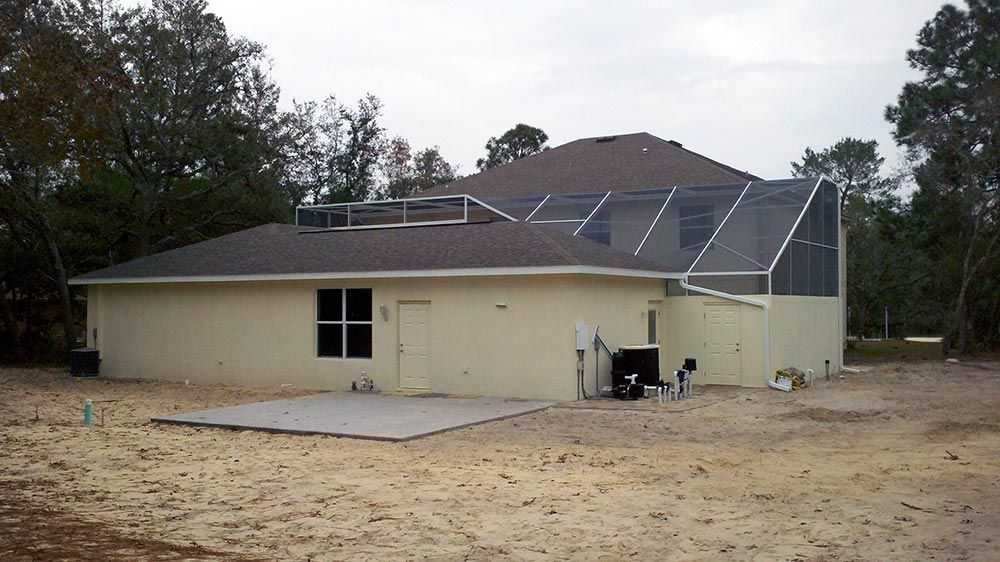 A house with a screened in porch is sitting in the middle of a dirt field