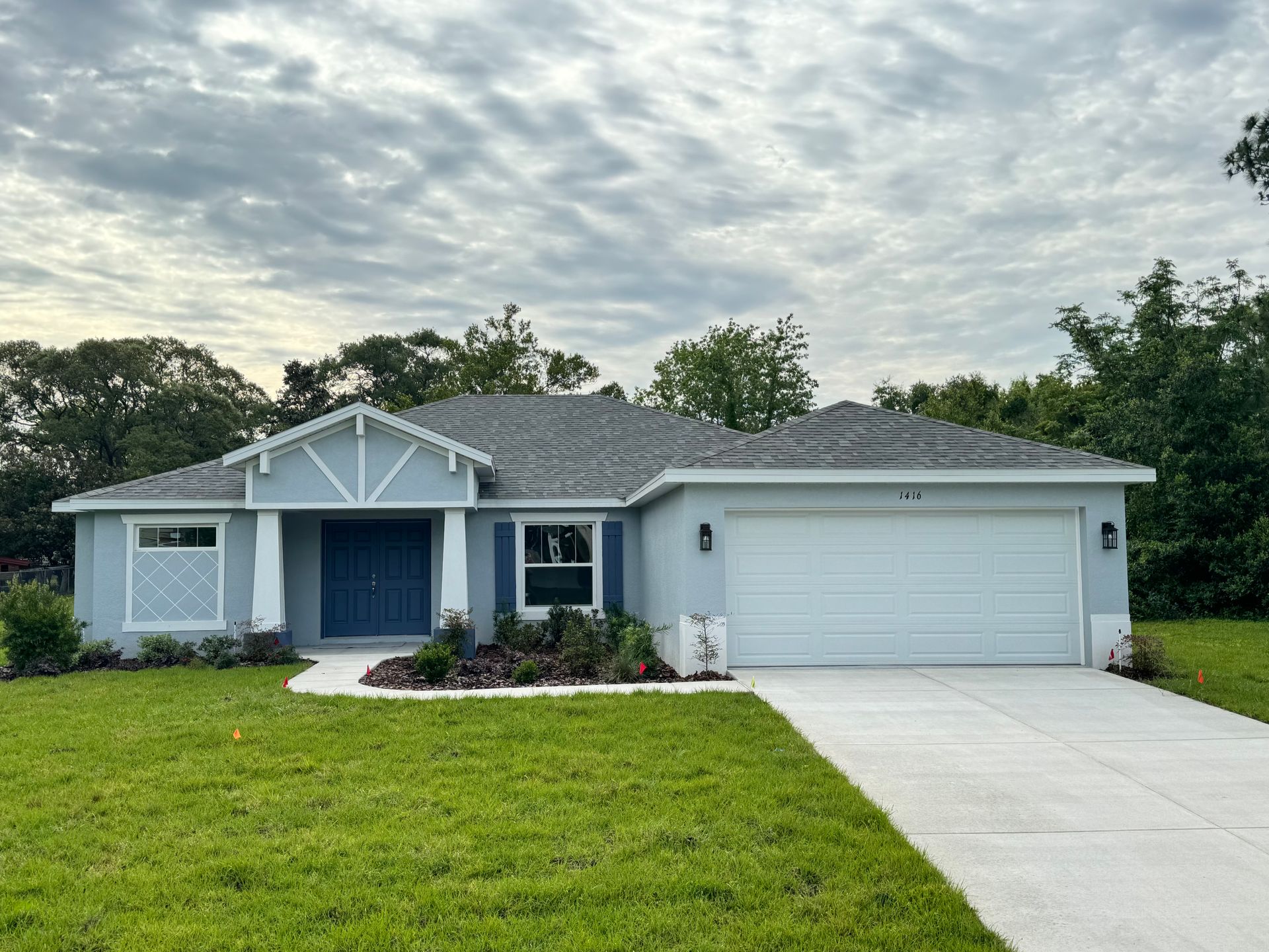 A blue house with a white garage door and trees in the background