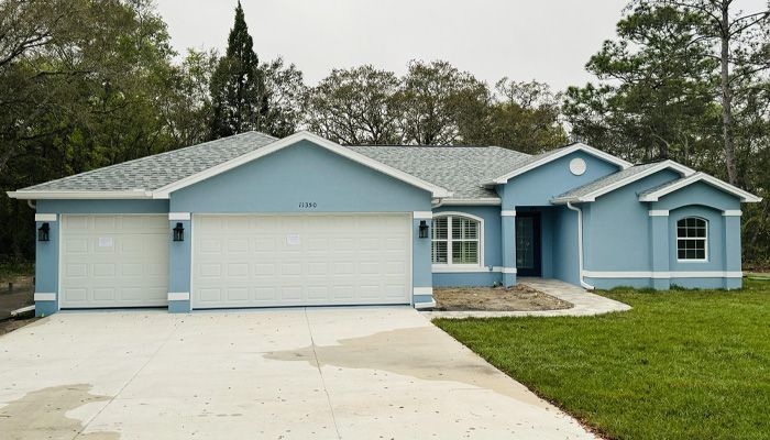 A blue house with white trim and a white garage door