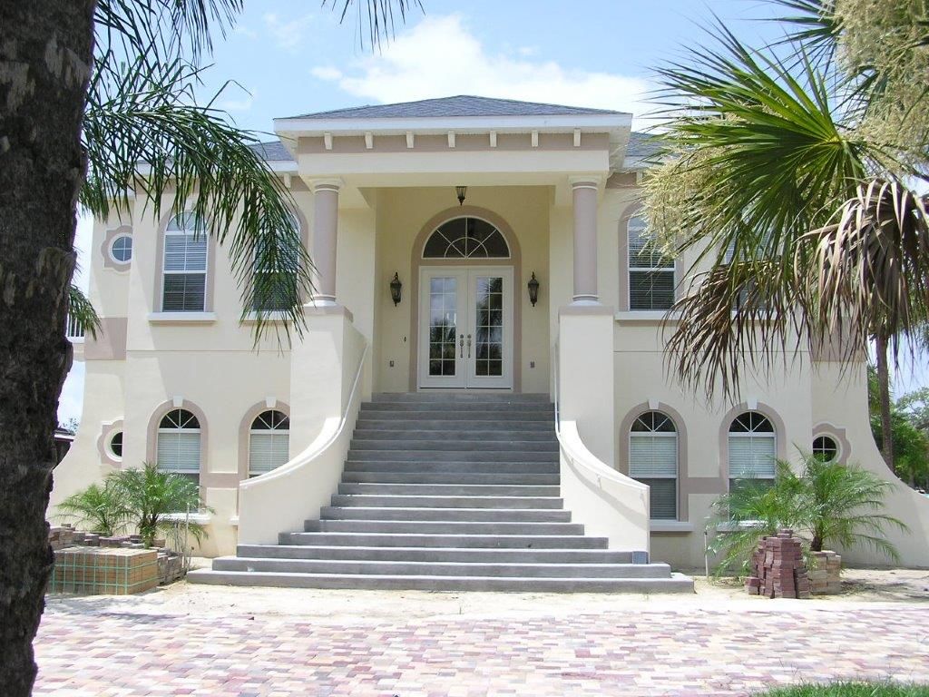 A large white house with stairs leading up to the front door