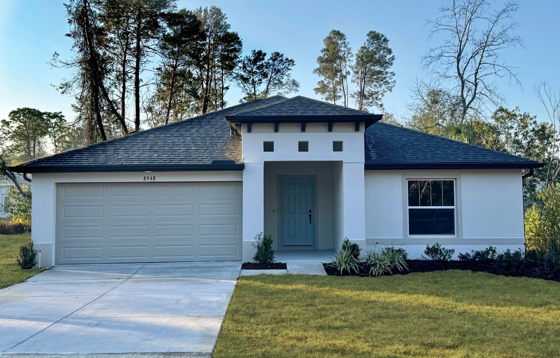 A white house with a black roof and a white garage door