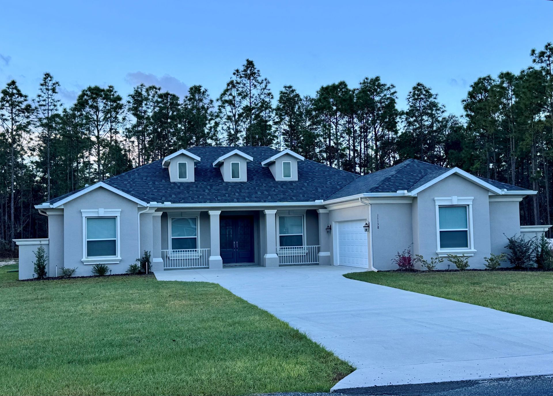 A large house with a blue roof is surrounded by trees