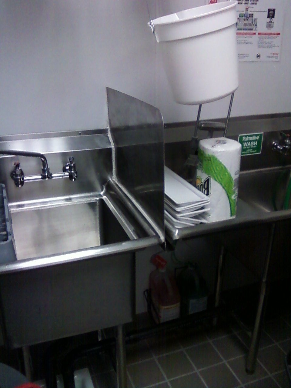A stainless steel kitchen sink with a paper towel holder