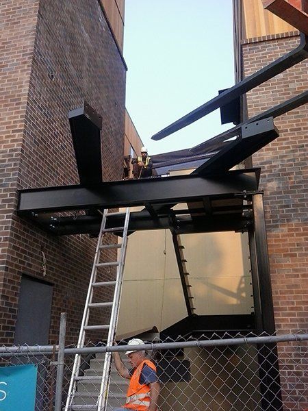 A man standing on a ladder in front of a brick building