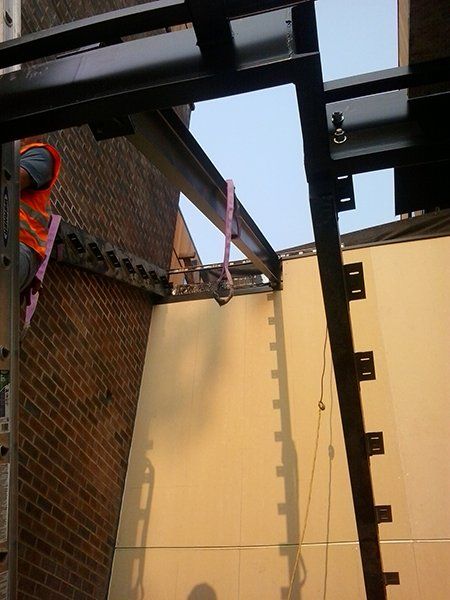 A man in an orange vest is working on a metal structure