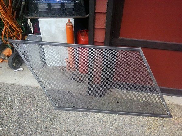 A metal screen is sitting on the ground in front of a red wall