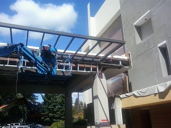 A blue crane is lifting a metal structure over a building