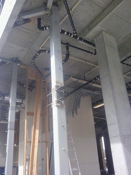 A building under construction with pipes hanging from the ceiling