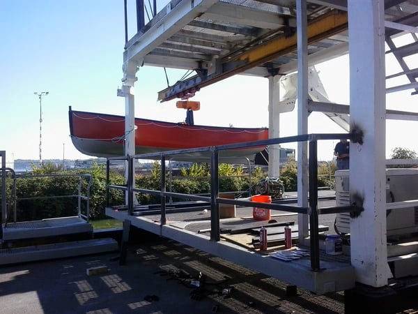 A boat is being lifted by a crane on a platform